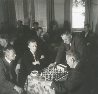 876594 Portret van mannen die aan het schaken zijn, met enkele toeschouwers, tijdens een vaderavond in een zaaltje van ...